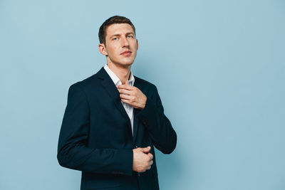 Portrait of businessman standing against blue background