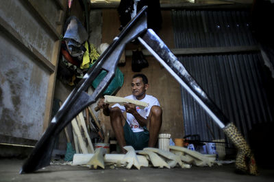 A craftsman finishes making a traditional salawaku shield weapon from cork wood in ternate city