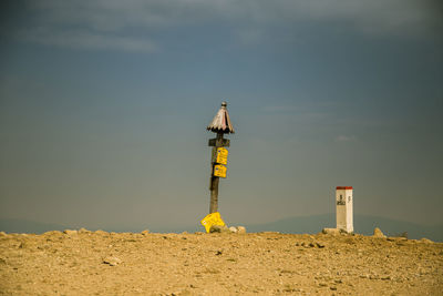 Lighthouse on beach against sky