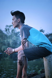 Young man looking at lake against sky