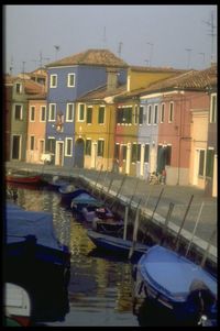 Boats moored in canal by buildings in city