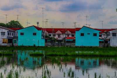 Houses by lake against sky