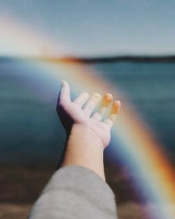 Close-up of hand against sea and sky