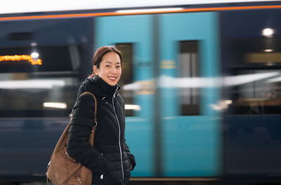 Portrait of smiling  woman standing against train