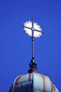 Low angle view of weather vane against clear blue sky