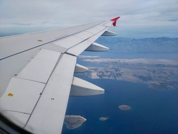 Airplane flying over mountains against sky