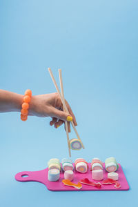 Female hand using chopsticks with candy sushi