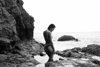 Woman standing in tidal pool on rocky pacific beach