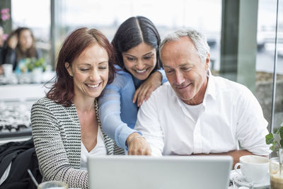 Happy business colleagues using laptop at restaurant