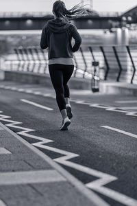 Rear view of woman running on road in city