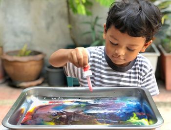 Boy dripping paint using color dropper in water