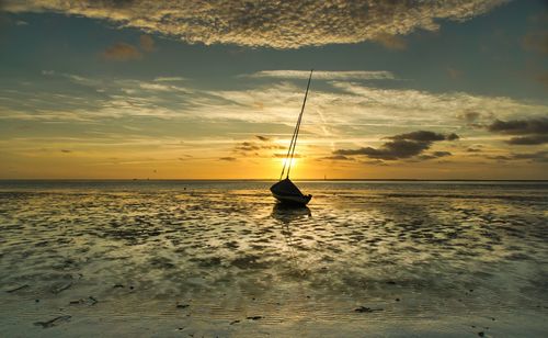 Silhouette sailboat on sea against sky during sunset