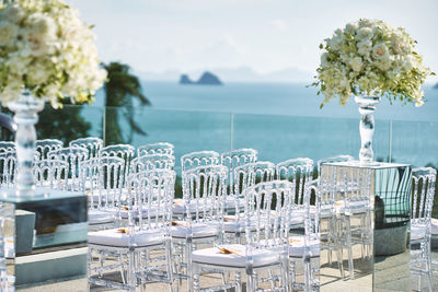 Plants and chairs on table by sea