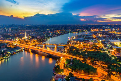 High angle view of illuminated bridge over river amidst buildings in city