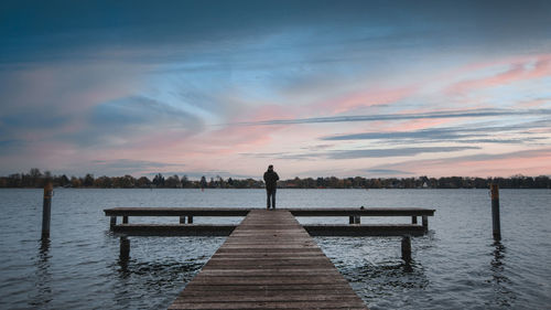 Man on jetty looking at sunset