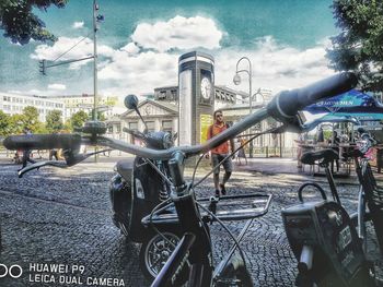 Bicycles on street in city against sky