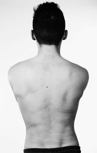 Rear view of shirtless man standing against white background