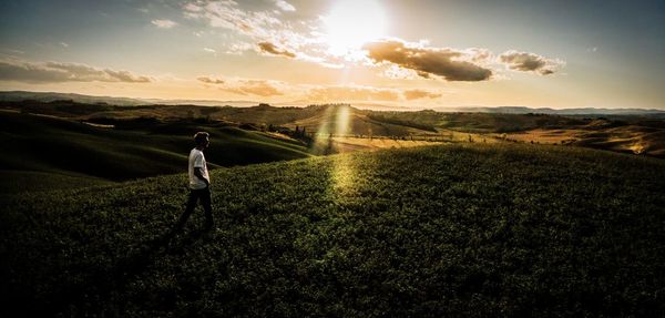 Man standing on field against sky during sunset
