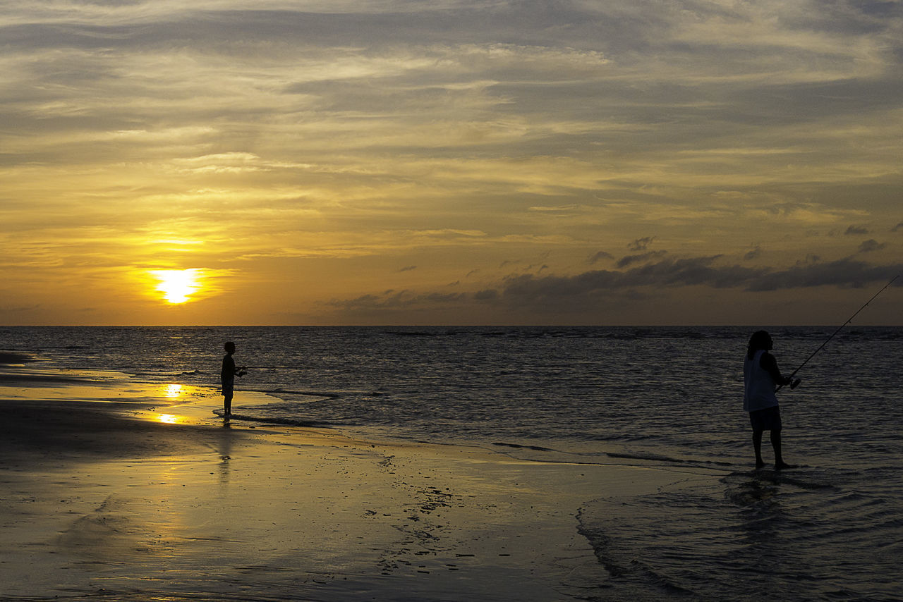 SILHOUETTE PERSON STANDING AT BEACH DURING SUNSET