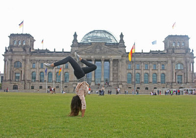 Statue of liberty in front of building against cloudy sky