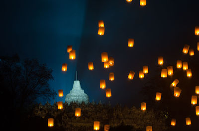 Low angle view of illuminated street light against building at night