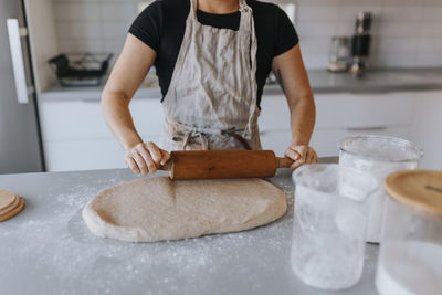 Mid section of woman rolling dough with rolling pin