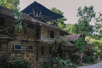 Low angle view of old building by trees against sky