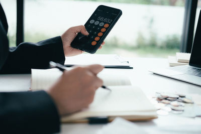 Midsection of person using mobile phone on table