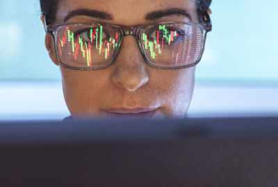 Stockbroker analyzing financial stock market with reflection on eyeglasses