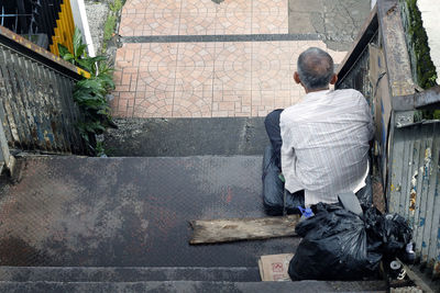 Rear view of man sitting on steps in city