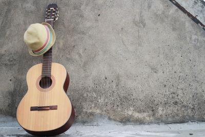 Close-up of guitar and sun hat against wall