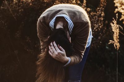 Woman with hand in hair bending outdoors