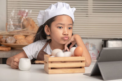 Portrait of cute girl sitting on table at home