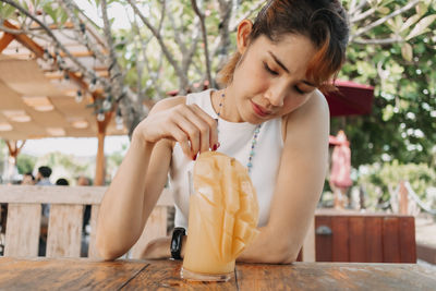 Young woman looking away while sitting on table