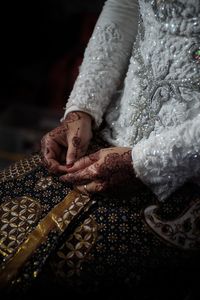 Midsection of bride with henna tattoo on hands