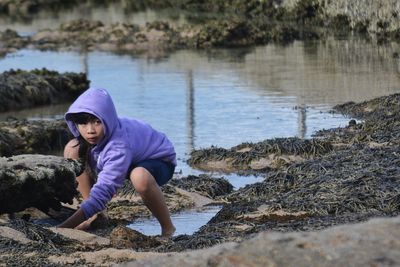 Portrait of boy standing on rock by water