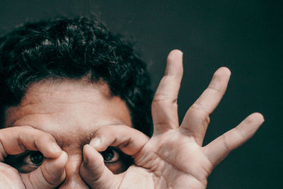 Cropped portrait of young man gesturing against black background