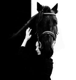 Portrait of woman with horse against black background