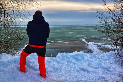 Rear view of man standing in sea during winter