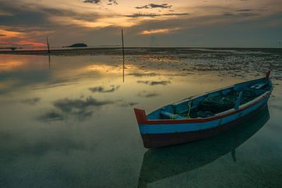 Boat moored on sea against sky during sunset