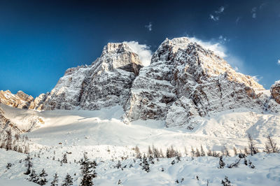 Scenic view of snow covered mountains against blue sky