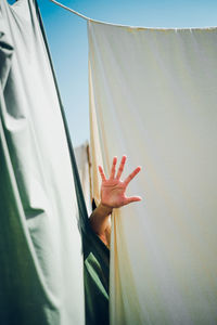 Cropped hand of person gesturing against textile