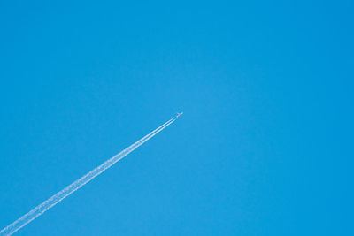 Low angle view of vapor trail against clear blue sky