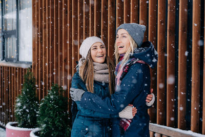 Adult female friends embracing and laughing rejoicing at the meet and snowy cold weather.
