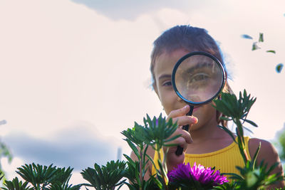 Portrait of woman holding sunglasses against sky