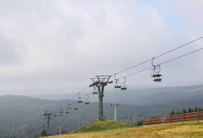 Overhead cable car over mountains against sky