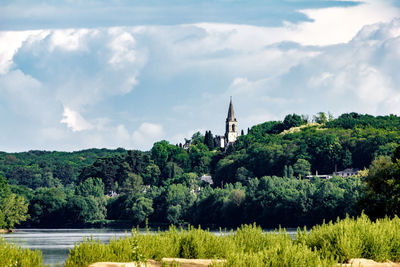 View of trees and buildings against cloudy sky