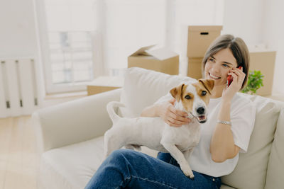 Portrait of woman with dog sitting on sofa