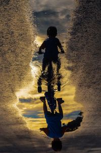 Silhouette people on shore against sky during sunset