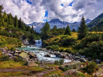 Scenic view of river stream amidst trees against sky